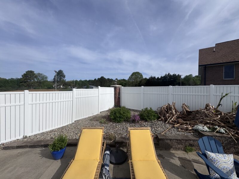 Overgrown planter bed with compacted soil and undefined edges in a Charlotte NC front yard before renovation