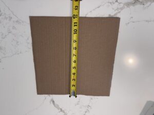 Measuring a one foot cardboard square to use as a lawn coverage reference